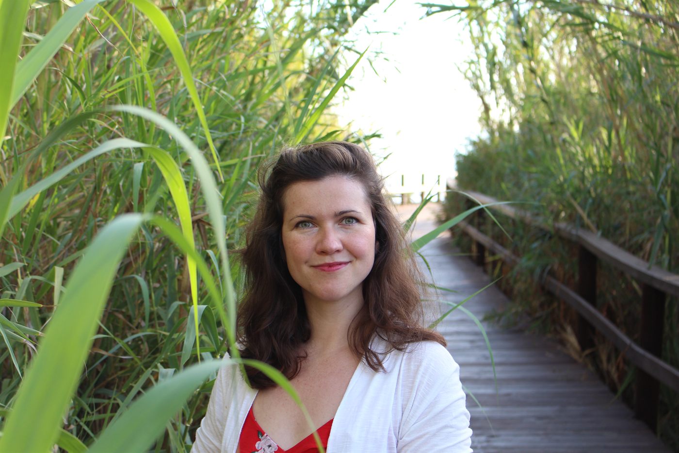 Rebecca Fackler auf einem Bohlenweg im Schilf, sie schaut in die Kamera